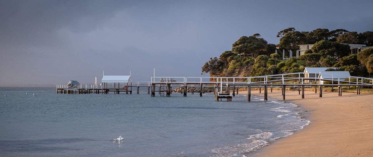 Sunlit beach with wooden pier and gentle waves